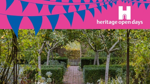 Hedges and slim trees stand either side of a central brick path